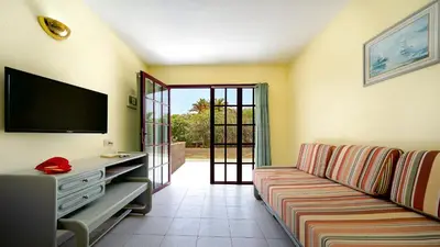 Una televisión o centro de entretenimiento en Bungalows Maspalomas Oasis Club - All Inclusive.