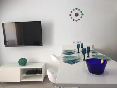 Una televisión o centro de entretenimiento en Las Arenas - apartamento moderno con vistas al mar y WiFi veloz de fibra óptica